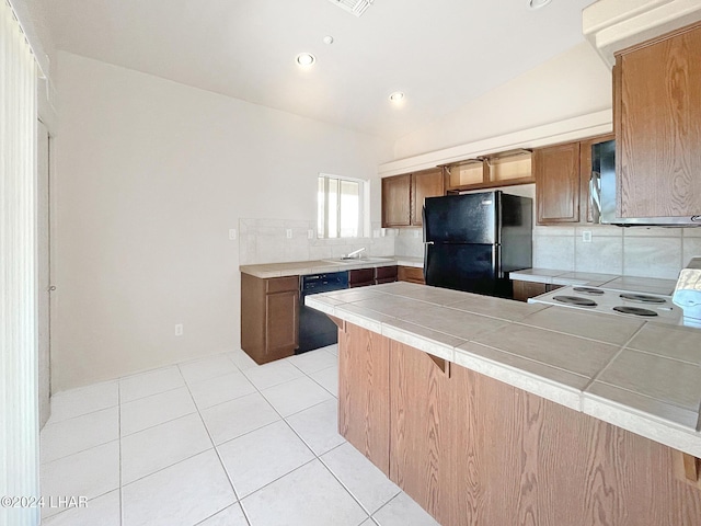 kitchen featuring sink, light tile patterned floors, tile counters, kitchen peninsula, and black appliances