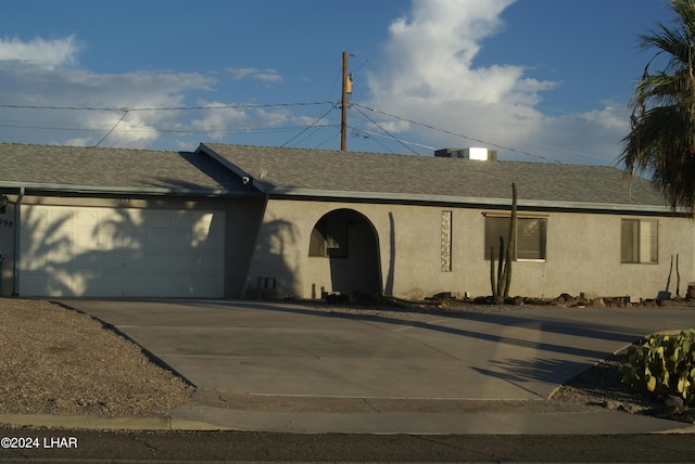 ranch-style house featuring a shingled roof, concrete driveway, an attached garage, and stucco siding