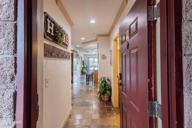 hallway with recessed lighting, stone finish flooring, baseboards, and ornamental molding