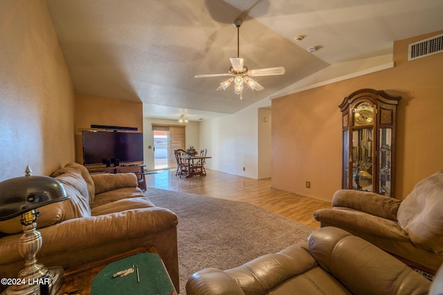 living room with ceiling fan, light hardwood / wood-style floors, and vaulted ceiling