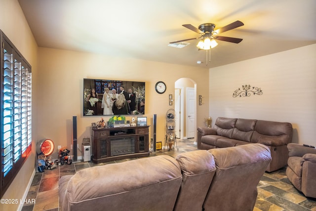 living room featuring arched walkways, ceiling fan, visible vents, and baseboards