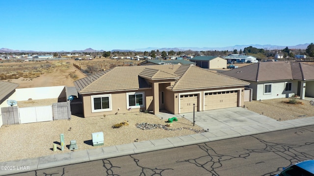 ranch-style house featuring an attached garage, fence, a mountain view, and a tiled roof