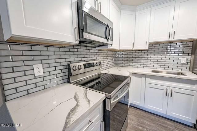 276 Lake Havasu Ave S Unit C31, Lake Havasu City, AZ 86403 - kitchen with stainless steel appliances, backsplash, white cabinetry, a sink, and wood finished floors