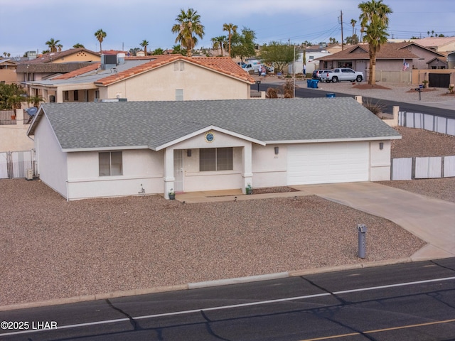 view of front of property with concrete driveway, fence, roof with shingles, and stucco siding