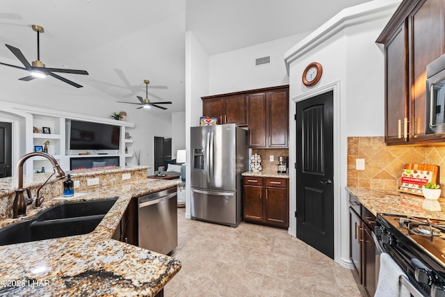 kitchen with light stone countertops, visible vents, a sink, stainless steel appliances, and dark brown cabinetry