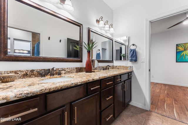 full bath featuring double vanity, baseboards, and a sink