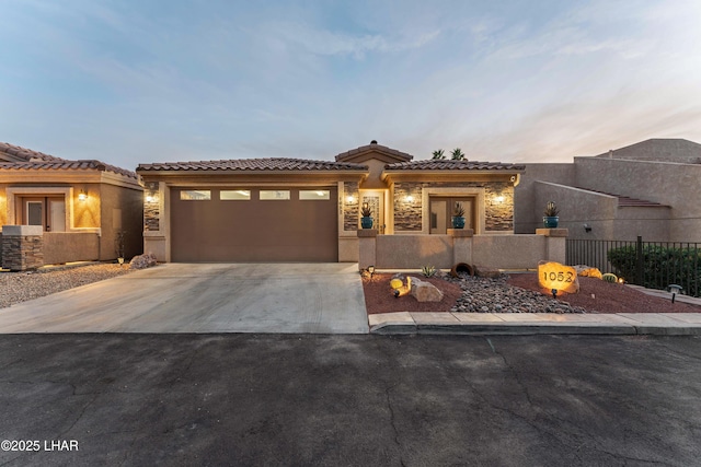 view of front of home featuring concrete driveway, stone siding, a garage, and a fenced front yard