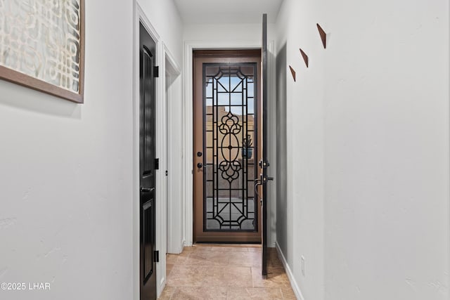 doorway to outside featuring stone finish floor and baseboards