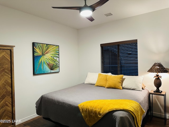 bedroom with a ceiling fan, wood finished floors, visible vents, and baseboards