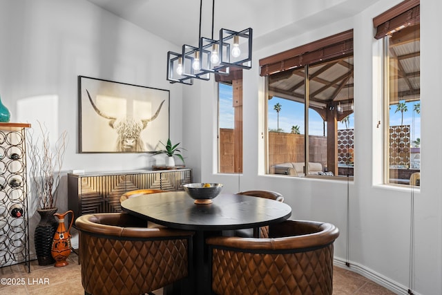 tiled dining area featuring baseboards and vaulted ceiling