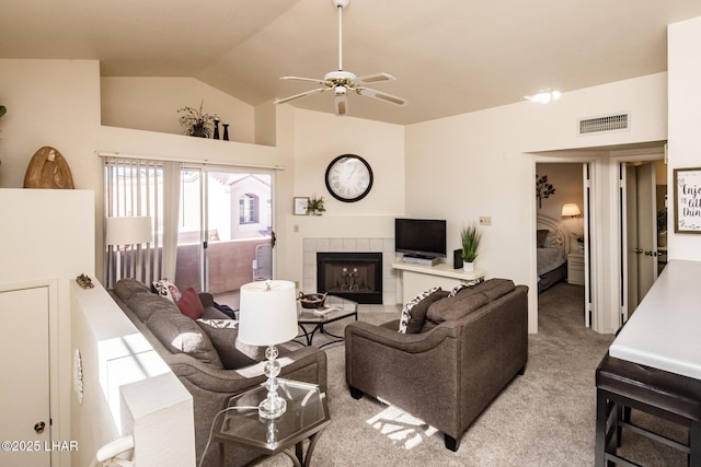 living room with light carpet, ceiling fan, vaulted ceiling, and a tile fireplace