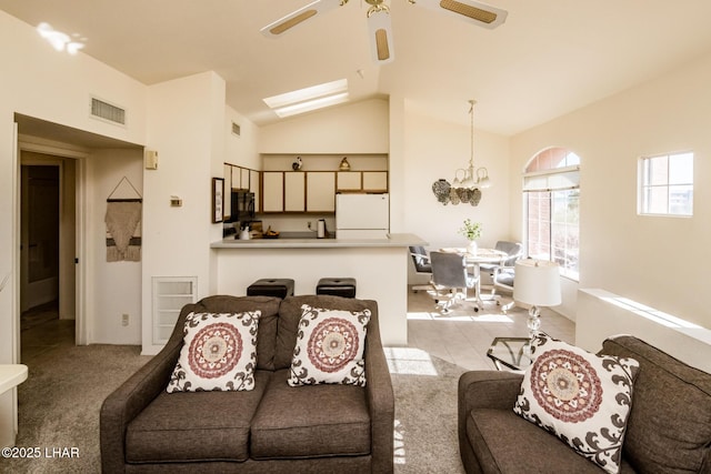 carpeted living room featuring ceiling fan with notable chandelier and vaulted ceiling