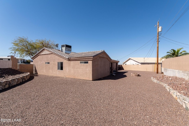 rear view of property with cooling unit, stucco siding, a tiled roof, and a fenced backyard