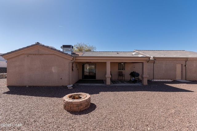 back of house with stucco siding, a patio, a fire pit, and a tiled roof