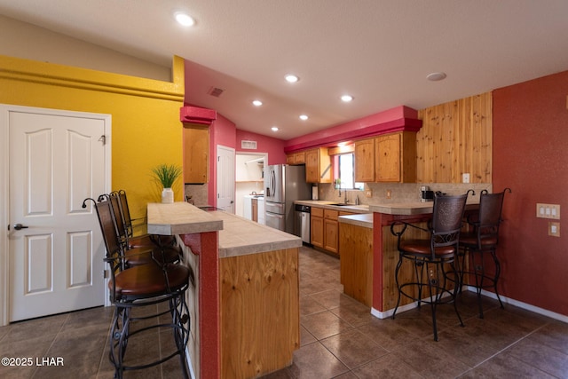 kitchen with appliances with stainless steel finishes, a breakfast bar area, a peninsula, and dark tile patterned flooring