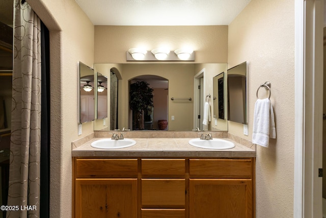 bathroom with double vanity, a textured wall, and a sink