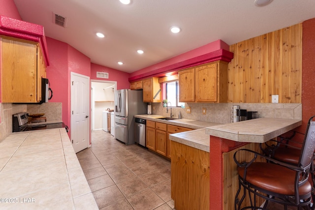 kitchen featuring visible vents, a peninsula, stainless steel appliances, and a sink