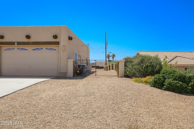 view of property exterior with fence, driveway, a gate, and stucco siding