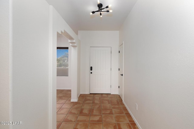 hall featuring baseboards and light tile patterned flooring