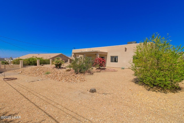 exterior space featuring stucco siding and fence