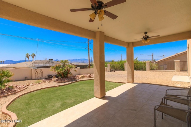 view of patio featuring a ceiling fan, a fenced backyard, and a mountain view