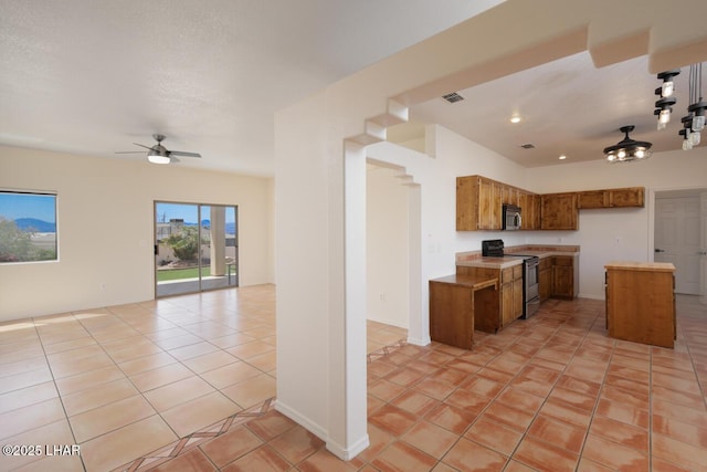 kitchen with brown cabinets, open floor plan, light tile patterned flooring, appliances with stainless steel finishes, and visible vents
