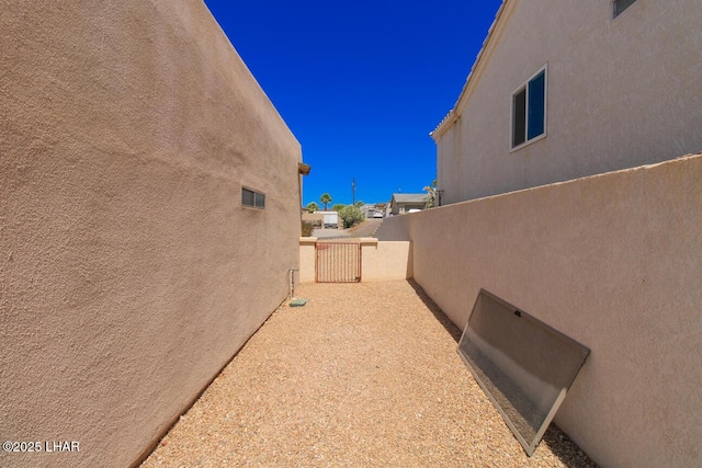 view of side of home featuring stucco siding and fence