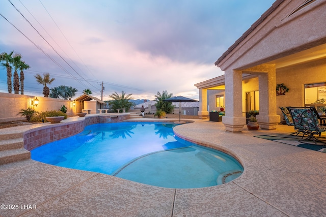 pool at dusk featuring a patio