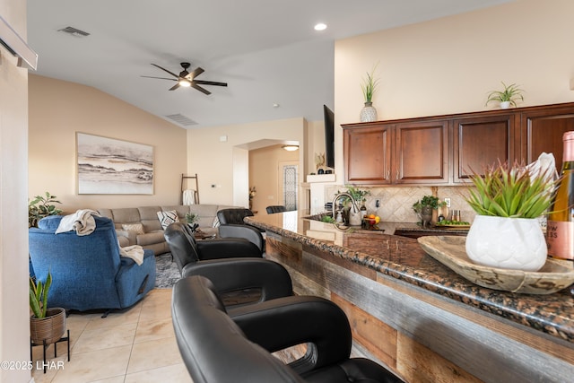 tiled living room with lofted ceiling and ceiling fan