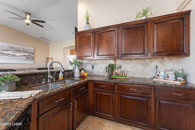 kitchen with sink, light tile patterned floors, ceiling fan, dark stone countertops, and backsplash