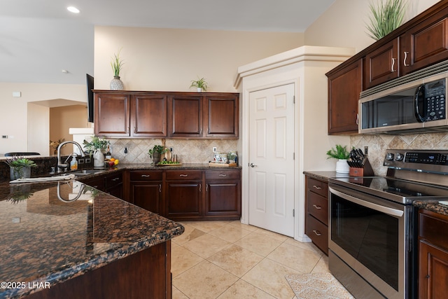 kitchen with light tile patterned floors, stainless steel appliances, sink, and dark stone countertops