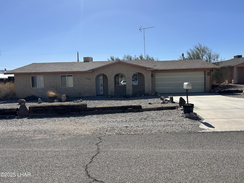 ranch-style house featuring central AC unit, stucco siding, an attached garage, and concrete driveway