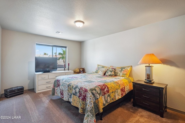 bedroom with dark carpet and a textured ceiling