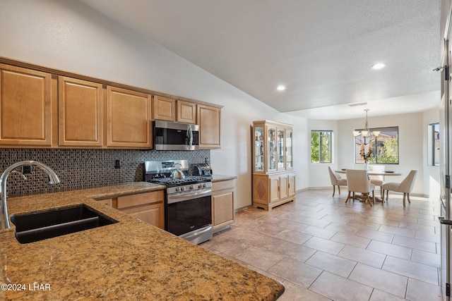 kitchen featuring vaulted ceiling, decorative light fixtures, sink, decorative backsplash, and stainless steel appliances