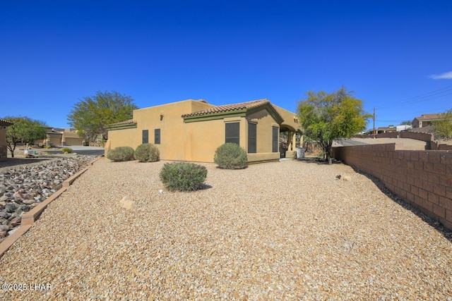 back of property with fence, a tiled roof, and stucco siding
