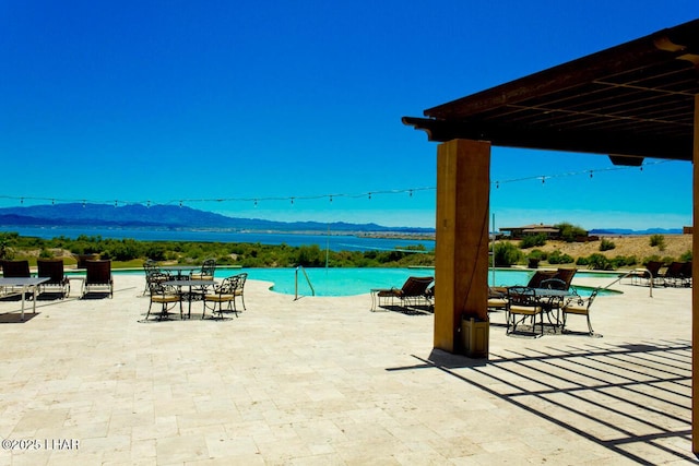 view of patio with a community pool and a water and mountain view