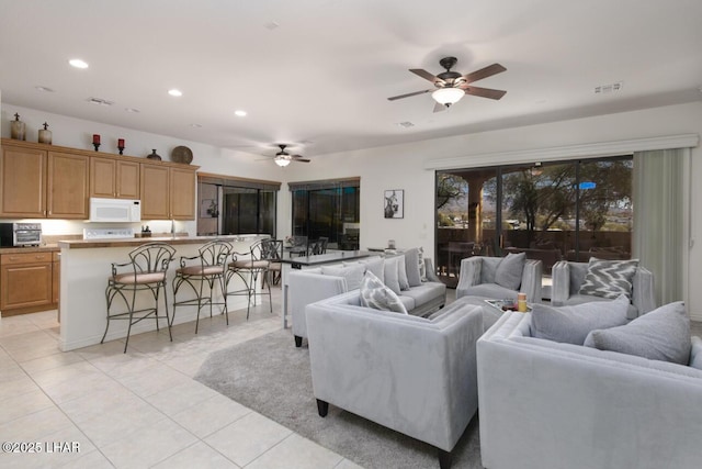living area featuring light tile patterned floors, a healthy amount of sunlight, a ceiling fan, and recessed lighting