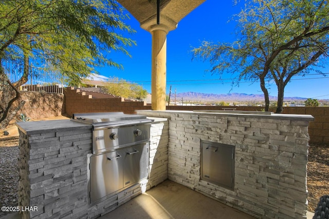 view of patio / terrace featuring exterior kitchen, fence, and a mountain view