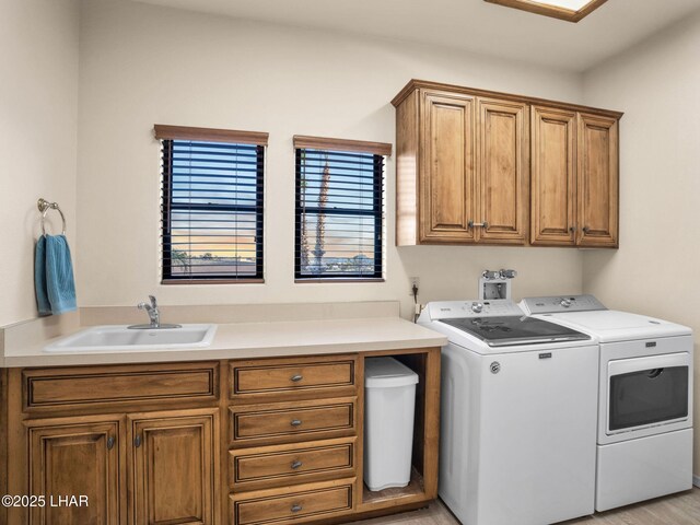 washroom with cabinets, washer and clothes dryer, and sink