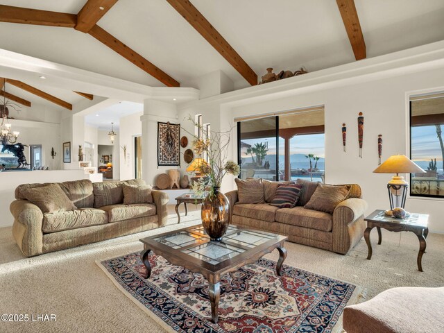 carpeted living room with a notable chandelier and lofted ceiling with beams