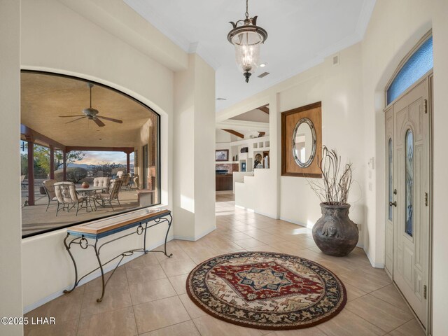 entrance foyer featuring crown molding, ceiling fan with notable chandelier, and light tile patterned floors