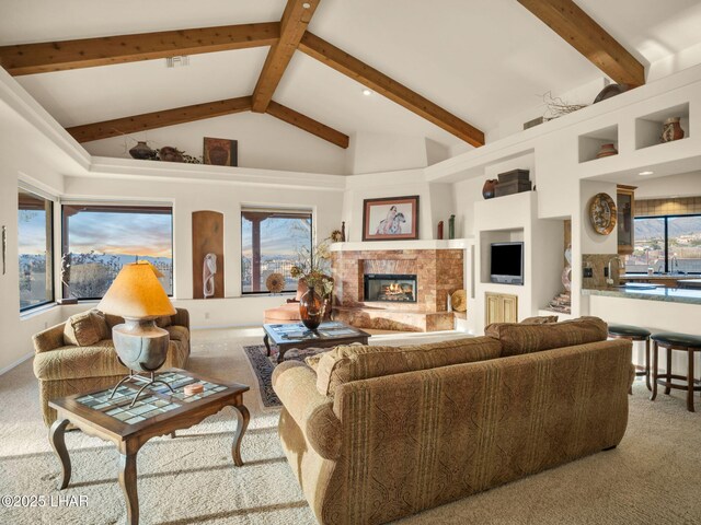 carpeted living room with a fireplace, high vaulted ceiling, and beam ceiling