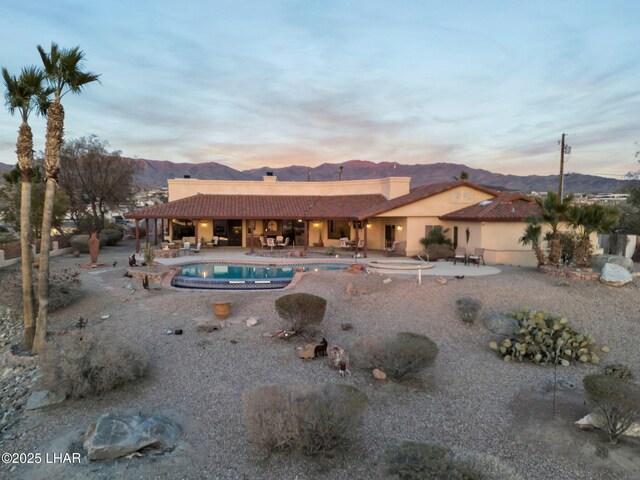 pool at dusk with a mountain view and a patio area