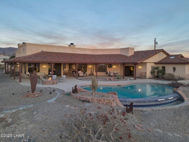 pool at dusk featuring a patio area and an outdoor fire pit