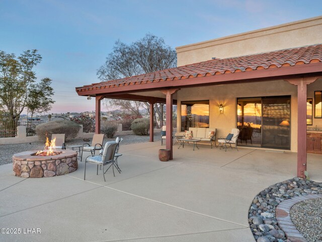 patio terrace at dusk with an outdoor living space with a fire pit