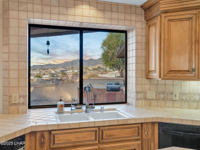 kitchen with sink, black dishwasher, tasteful backsplash, tile counters, and a mountain view