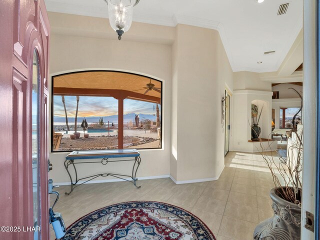 tiled foyer entrance with crown molding and ceiling fan