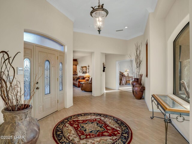 tiled entryway featuring a notable chandelier and ornamental molding