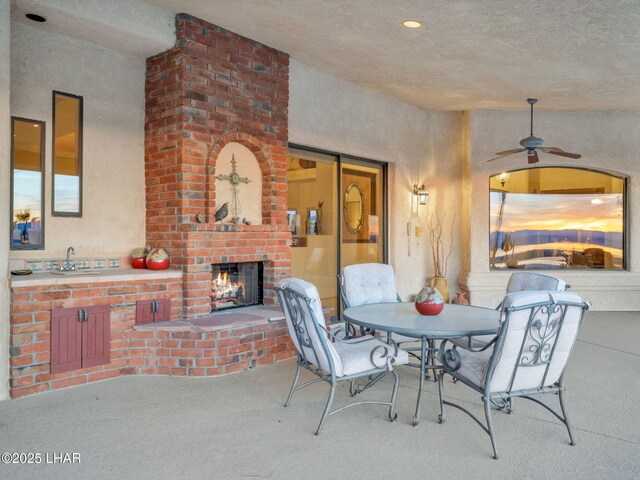 view of patio with an outdoor brick fireplace and ceiling fan