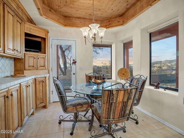 tiled dining area featuring a chandelier, wood ceiling, a healthy amount of sunlight, and a raised ceiling